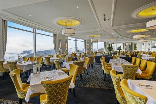 a restaurant with tables and yellow chairs and windows at Hydro Majestic Blue Mountains in Medlow Bath