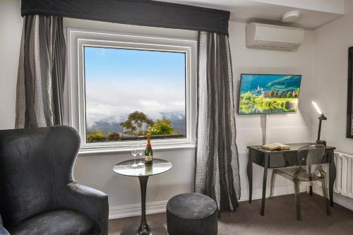 a living room with a window and a chair and a table at Hydro Majestic Blue Mountains in Medlow Bath