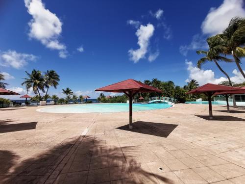 a swimming pool with umbrellas in a resort at Studio Coco Zen in Sainte-Anne