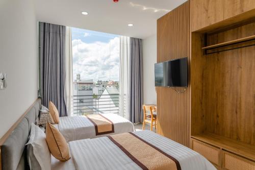 um quarto de hotel com duas camas e uma janela em Khang Hy Hotel em Buôn Enao