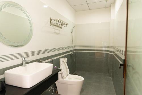 a bathroom with a sink and a toilet and a mirror at Khang Hy Hotel in Buôn Enao
