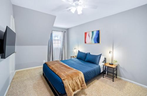a bedroom with a blue bed and a flat screen tv at Close to St. Francis Hospital • 4 Smart Tvs • Pool • Patio in Tulsa