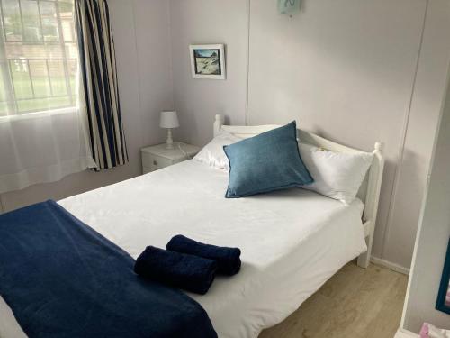 a white bed with blue pillows on top of it at Beach Cottage in Kleinmond