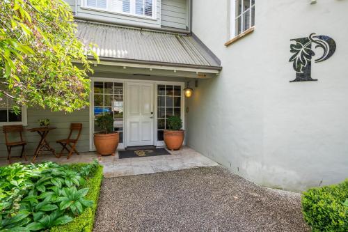 a front door of a white house with potted plants at Parklands Country Gardens & Lodges Blue Mountains in Blackheath