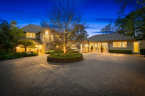 a house with a tree in the middle of a driveway at Parklands Country Gardens & Lodges Blue Mountains in Blackheath