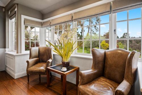 two chairs and a table in a room with windows at Parklands Country Gardens & Lodges Blue Mountains in Blackheath