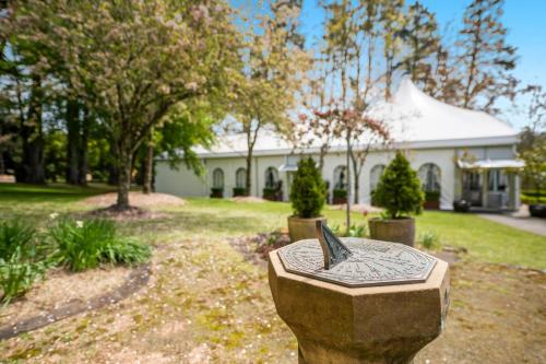 a stone bench in front of a white house at Parklands Country Gardens & Lodges Blue Mountains in Blackheath