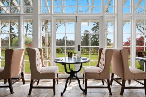 a conservatory with a table and chairs and windows at Parklands Country Gardens & Lodges Blue Mountains in Blackheath
