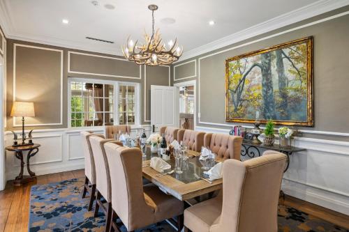 a dining room with a table and chairs and a painting at Parklands Country Gardens & Lodges Blue Mountains in Blackheath