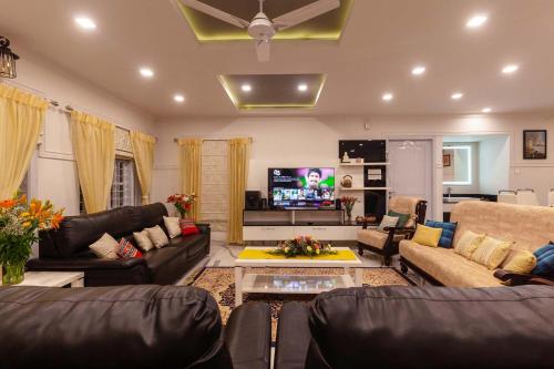 a living room with couches and a tv at StayVista at Aashirwaad Villa in Coonoor