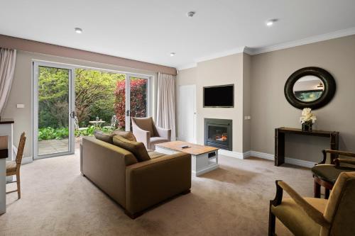 a living room with a couch and a fireplace at Parklands Country Gardens & Lodges Blue Mountains in Blackheath