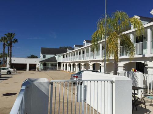 a white building with a fence and a palm tree at Anastasia Inn - Saint Augustine in Saint Augustine