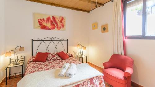sypialnia z łóżkiem i czerwonym krzesłem w obiekcie Espina Rural Almogía by Ruralidays w mieście Almogía
