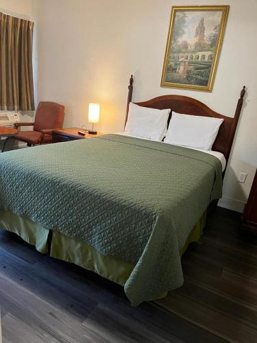 a bedroom with a large bed with a green comforter at Economy Inn Paso Robles in Paso Robles