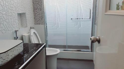 uma casa de banho com um WC e uma cabina de duche em vidro. em Avana Hills Boracay Prime Grand Suite em Boracay