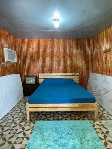 a bedroom with a blue bed and a wooden wall at West Sahara Beach House in Cabangan