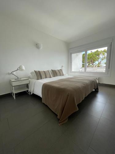 a white bedroom with a large bed and a window at Viva Sitges - Sitges View in Sitges