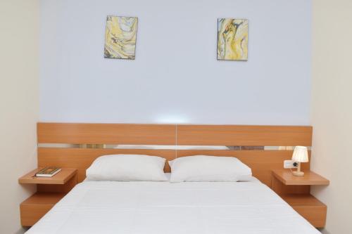ein Schlafzimmer mit einem weißen Bett und zwei Nachttischen in der Unterkunft Homestay 82 Syariah Palembang in Palembang