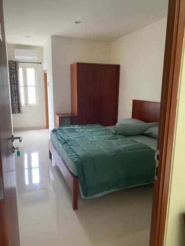 um quarto com uma cama com um edredão verde em Rumah Pondok Pinang em Jakarta