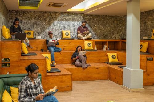 eine Gruppe von Personen, die auf Bänken in einem Raum sitzen in der Unterkunft The Hosteller Delhi in Neu-Delhi