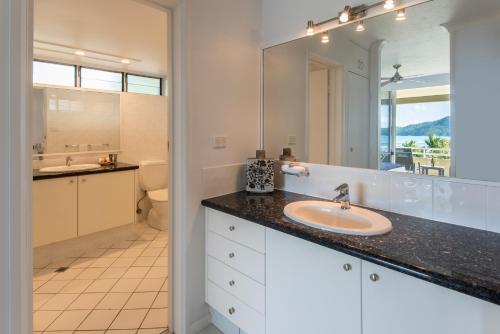 La salle de bains est pourvue d'un lavabo et d'un grand miroir. dans l'établissement Hibiscus Apartments on Hamilton Island by HIHA, à Île Hamilton