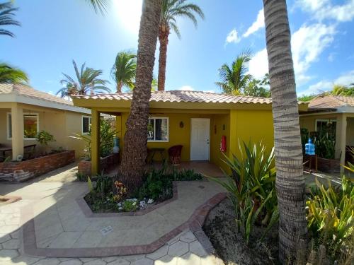 une maison jaune avec des palmiers devant elle dans l'établissement Coco Cabanas Loreto, à Loreto