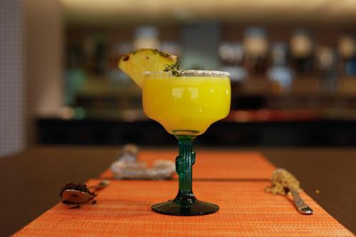 a yellow drink in a green glass on a table at Premier Inn Doha Airport in Doha
