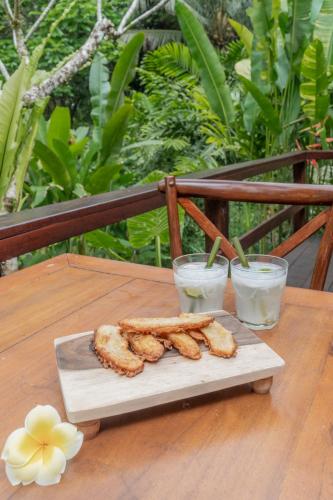 a plate of food on a table with two glasses of milk at Galalima Glamping by AGATA in Tabanan