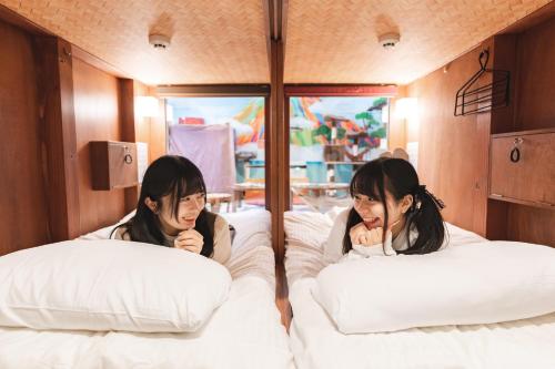 two girls laying in beds in a trailer at Cat Spa & Cat Ryokan by Neco Republic Osaka in Osaka
