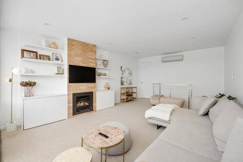 uma sala de estar com um sofá e uma lareira em Sandy@Village - newly renovated + bay views em Sandringham