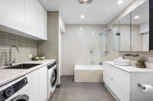 uma cozinha branca com um lavatório e uma máquina de lavar roupa em Sandy@Village - newly renovated + bay views em Sandringham