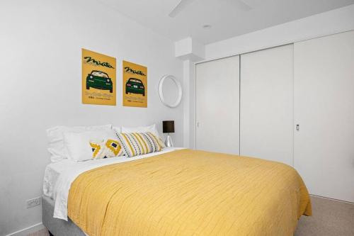 a bedroom with a yellow bed with two posters on the wall at Sandy@Village - newly renovated + bay views in Sandringham
