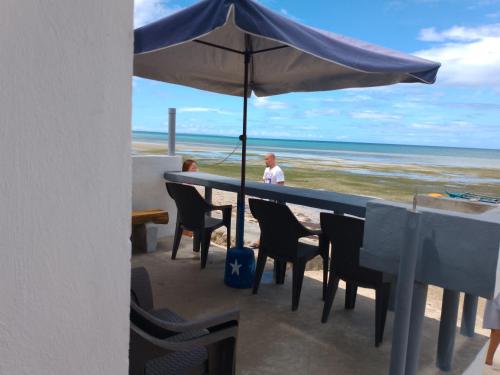 Daanbantayan的住宿－Little Sanity Beach house，一位坐在桌子上,在海滩上拿着一把遮阳伞的人