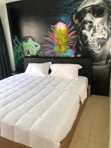 a bedroom with a large white bed in front of a painting at The Green Spot in Pattaya