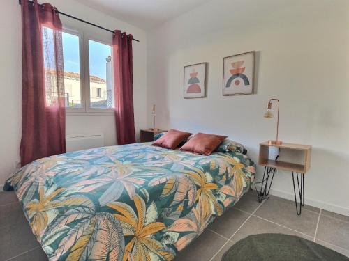 um quarto com uma cama com um cobertor colorido e uma janela em Maison calme-golf em Montboucher-sur-Jabron