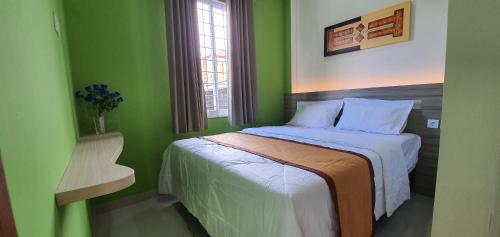 - une chambre verte avec un lit et une chaise dans l'établissement REG GUESTHOUSE, à Tanjungredep