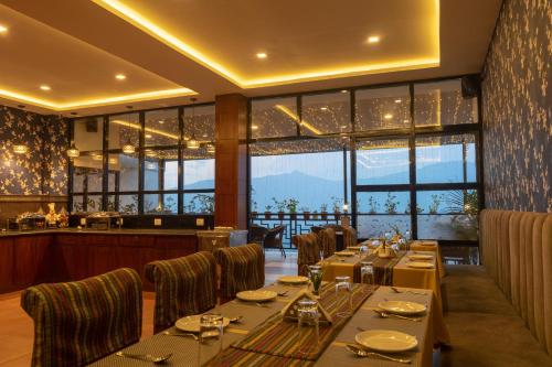 uma sala de jantar com mesas, cadeiras e janelas em HOTEL SHINKHAM GRAND em Gangtok