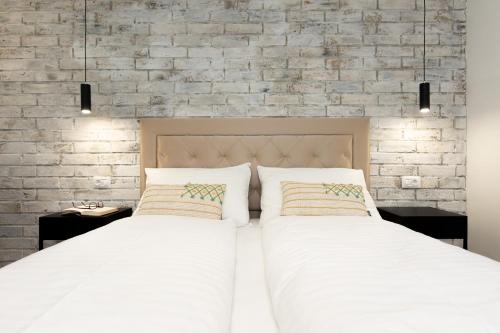 a bedroom with two beds and a brick wall at Ela in Rijeka