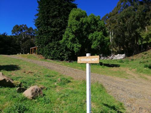 a street sign on a dirt road in a field at Glenwood Akaroa Bush Retreat - Totara Hut in Akaroa