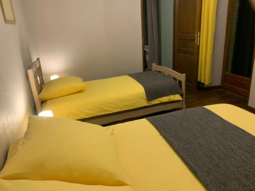 two beds in a small room with yellow beds at Maison indépendante à la campagne in Courcelles-sur-Vesle