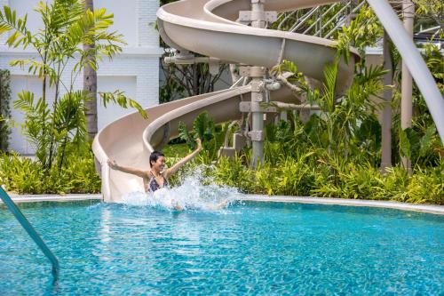 une femme sur un toboggan aquatique dans une piscine dans l'établissement Outrigger Koh Samui Beach Resort - SHA Extra Plus, à Lamai