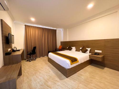 Hotel Sterling Inn في بانغالور: غرفه فندقيه سرير وتلفزيون