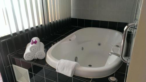 a bath tub in a bathroom with black tiles at Regal Port Douglas in Port Douglas