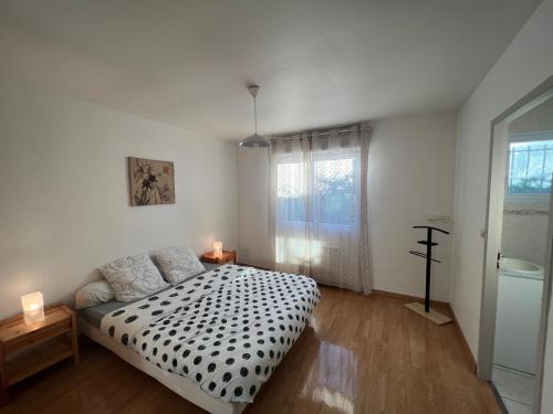 Schlafzimmer mit einem schwarzen und weißen Bett und einem Fenster in der Unterkunft Maison Royan 3 chambres avec salle d'eau, piscine in Royan