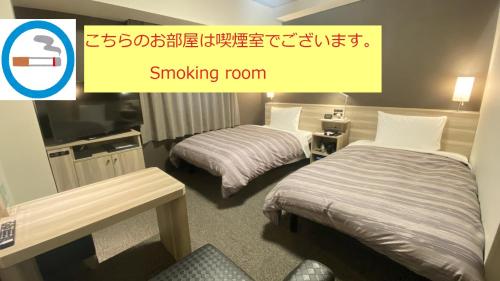 a hotel room with two beds and a sign that reads smoking room at Route Inn Grantia Tokai Spa&Relaxation in Tokai