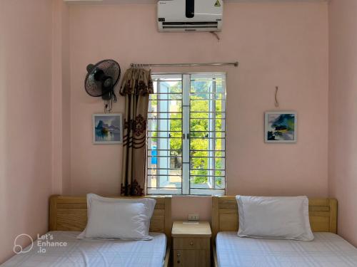 a bedroom with two beds and a window at Cat Ba Sweet Potato Homestay in Cat Ba