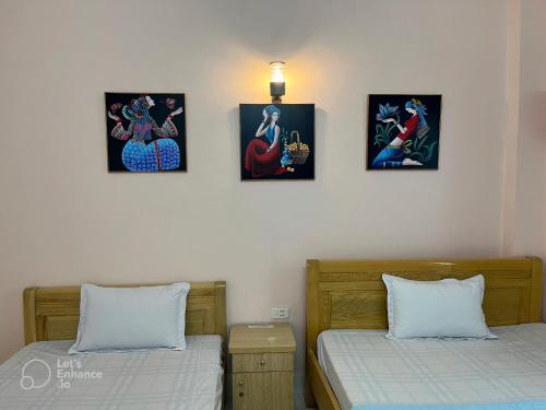 two beds in a room with four pictures on the wall at Cat Ba Sweet Potato Homestay in Cat Ba