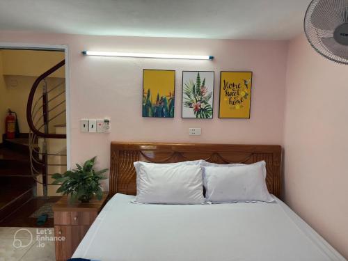 een slaapkamer met een bed met witte lakens en foto's aan de muur bij Cat Ba Sweet Potato Homestay in Cat Ba
