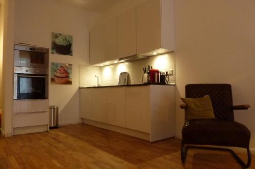 uma cozinha com armários brancos e uma cadeira num quarto em Apartment P1 in Berlin-Friedrichshain em Berlim