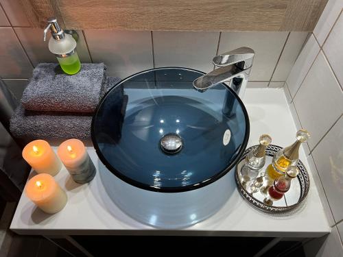 a bathroom sink with a blue glass bowl and candles at Ονειρεμένο διαμέρισμα Ν1 in Theologos